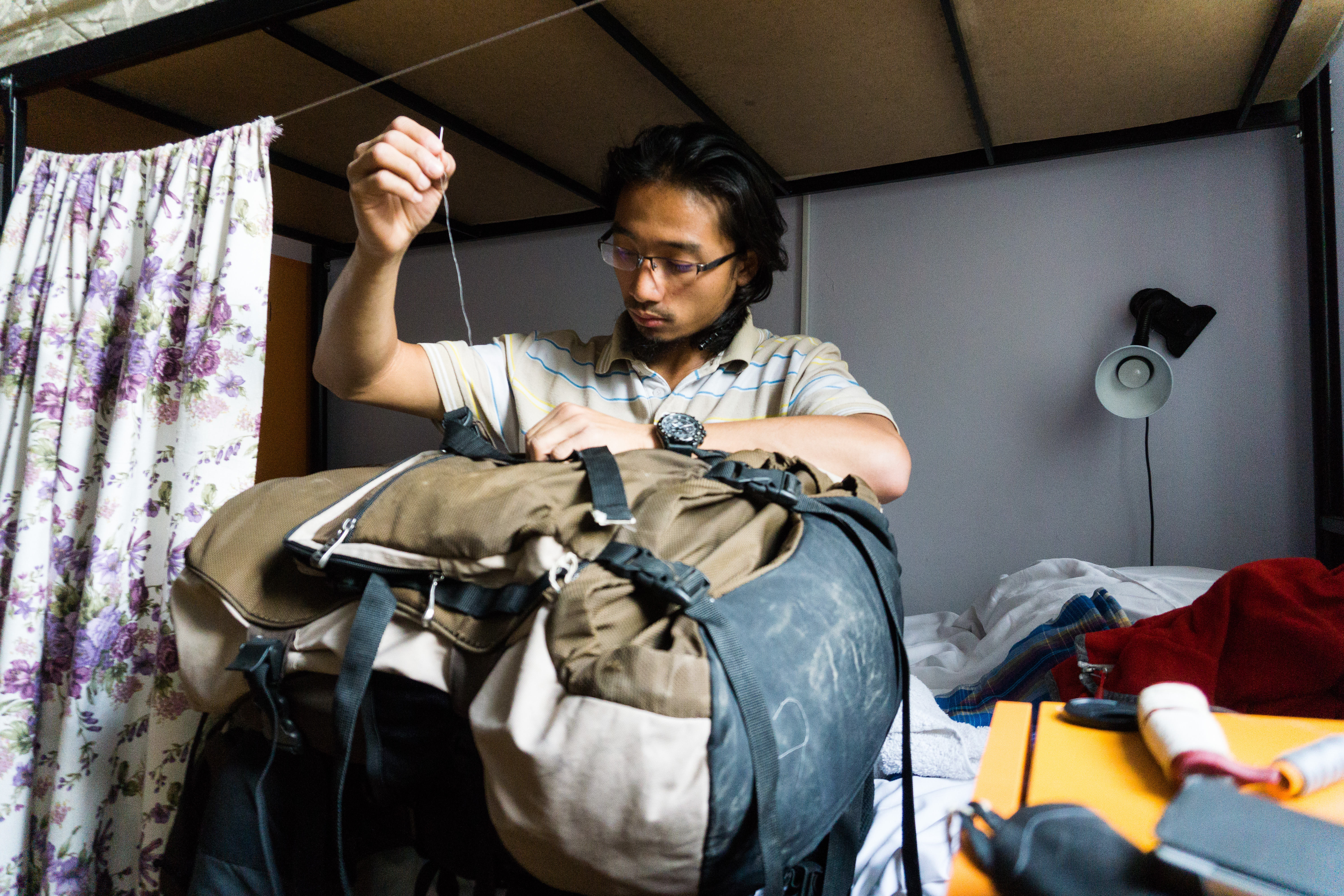 a guy focusing on mending his tore backpack